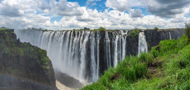 Zambezi Nehri 'nin Victoria Şelalesi manzarası, Zambiya sınırı ve mavi gökyüzü ve dramatik bulutlarla Zimbabwe.