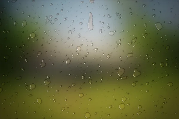 Gotas de lluvia sobre vidrio sobre fondo natural —  Fotos de Stock