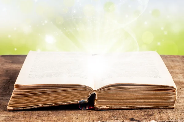 Open book on a wooden table with light effects