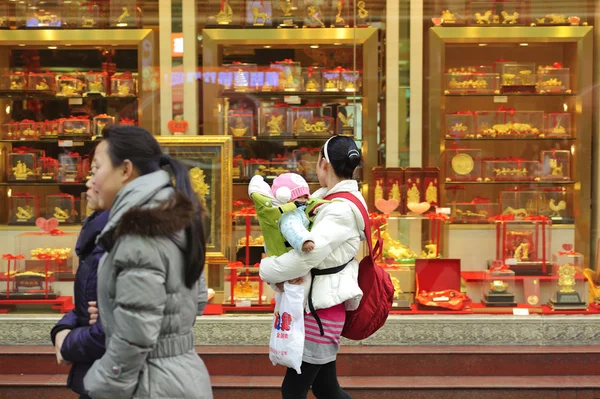 A mother holding a child to look in the window of a gold shop — Stock Photo, Image