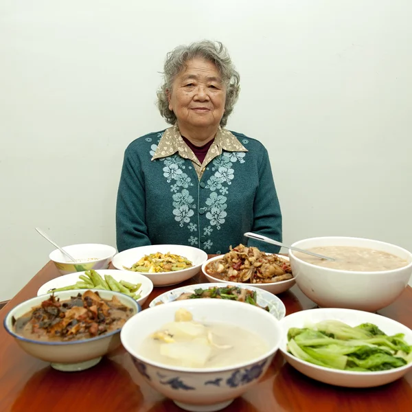 Siedząc przy stole, szczęśliwa babcia — Zdjęcie stockowe