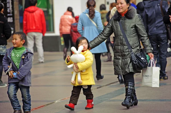 Mother and daughter pass through a busy pedestrian shopping street — Stock Photo, Image