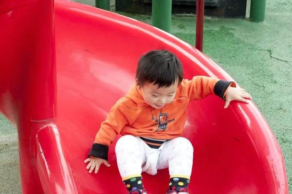 Baby spelen op het glijden van de Raad van bestuur — Stockfoto