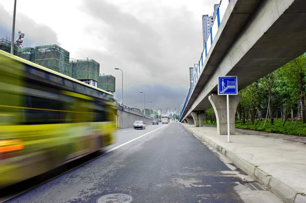 Véhicules à grande vitesse sentiers brouillés sur les routes urbaines sous le passage supérieur — Photo