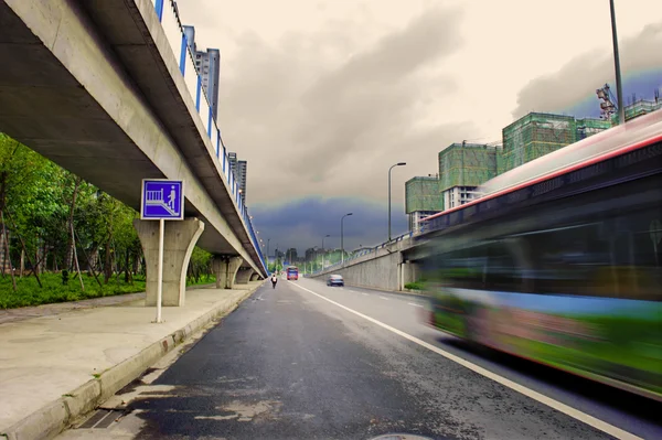 Veículos de alta velocidade com trilhas turvas em estradas urbanas sob viaduto — Fotografia de Stock