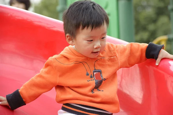 Baby spelen op het glijden van de Raad van bestuur — Stockfoto