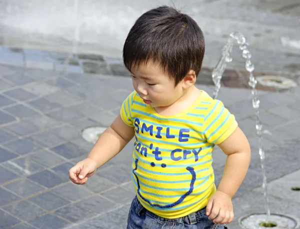 Un bambino carino sta giocando fontana — Foto Stock