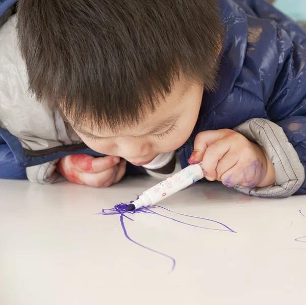 Et søtt barn maler på bordet. – stockfoto