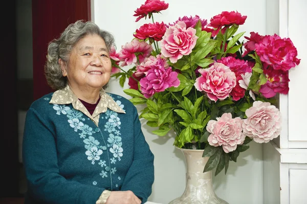 Çiçek yanında mutlu büyükanne — Stok fotoğraf