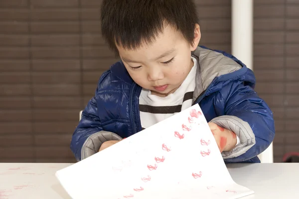 Een schattige baby is schilderen op tafel — Stockfoto