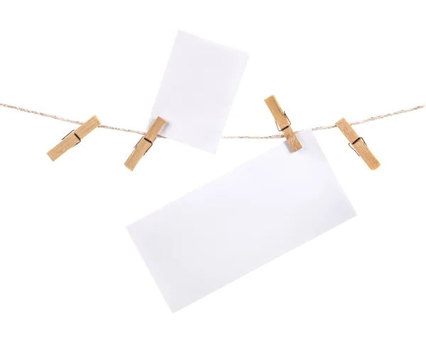 Wooden clothespins on rope and blank paper sheets — Stock Photo, Image
