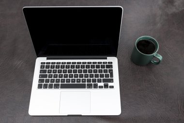 Dumanı tüten kahve ile bir masa üstünde laptop