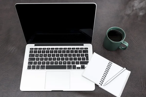 Laptop em uma mesa com um notebook e café fumegante — Fotografia de Stock