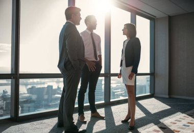 Bir grup başarılı iş adamı ofis önünde konuşuyor. Şehre bakan pencereler.