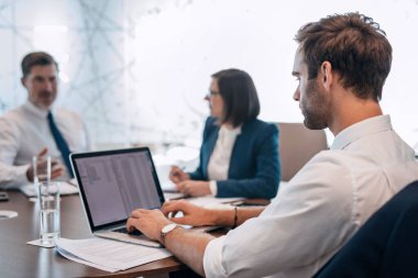 Bir grup başarılı iş adamı ofis yönetim kurulunda masa başında çalışırken birlikte konuşuyorlar.