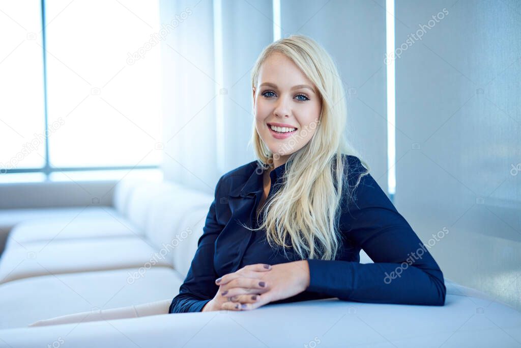 Portrait of a smiling young businesswoman sitting on a sofa in a modern office