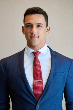 Donanma elbisesi ve kırmızı kravat takan odaklanmış genç bir işadamının portresi bir ofisin duvarına yaslanmış duruyor.