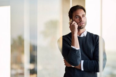 Ofisinde duran ve bir müşterisiyle cep telefonuyla konuşan odaklanmış genç bir girişimci.