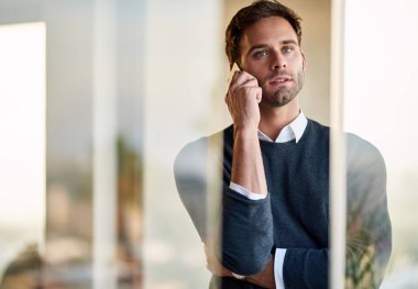 Genç işadamı ofisinde tek başına duruyor ve bir müşterisiyle konuşuyor.