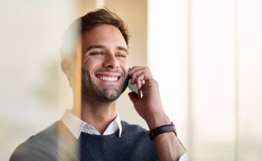 Ofisinde durup müşteriyle konuşurken gülümseyen genç bir işadamı.