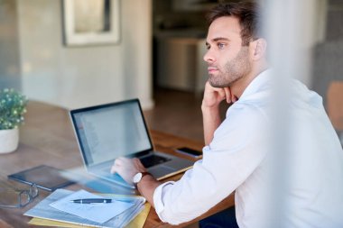Genç işadamı evde bir masada oturup bilgisayarla evrak işleriyle uğraşırken işini düşünüyor.
