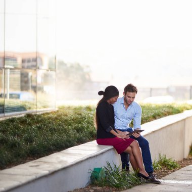 Ofislerinin önünde otururken dijital tabletle çalışan iki farklı genç iş adamı. 