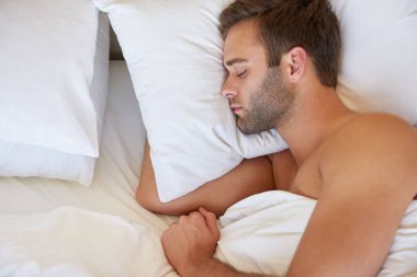 Sakallı yakışıklı bir gencin yukarıdan çekimleri. Beyaz keten kumaşlı yumuşak bir yastıkta huzur içinde uyuyor.