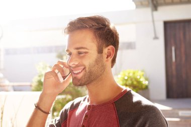 Kafasında ve omuzlarında, telefonuyla evinin önünde gülümseyen yakışıklı bir genç resmi var.