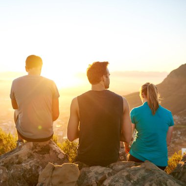 Dikiz aynasından üç arkadaş sessizce kayalıklarda oturup güneşin doğuşunun tadını çıkarıyorlar.
