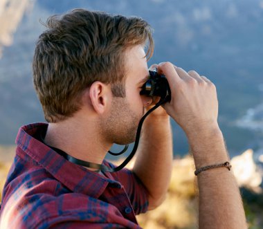 Dürbünle doğa yolunda duran yakışıklı bir gencin yakından görünüşü.