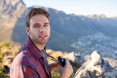 Dürbün tutan yakışıklı genç adam ve doğal bir setin içinde dururken kısaca geriye bakıyor.
