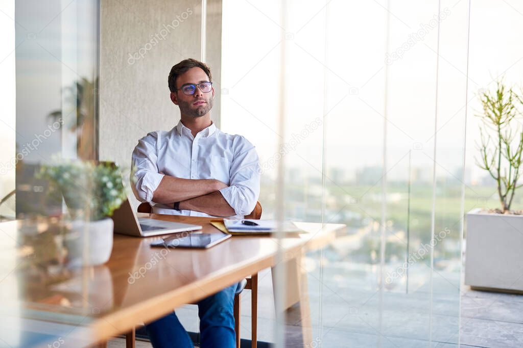 Casually dressed young businessman deep in thought while working on a laptop at a table at home  