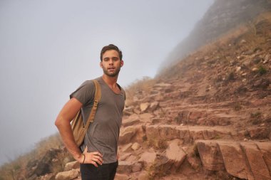 Kayalık bir dağ yamacında yakışıklı bir yürüyüşçünün portresi.