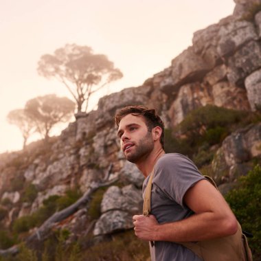 Arkasındaki sisli dağ manzaralı doğa yolunda yakışıklı bir adamın alçak açılı çekimi.