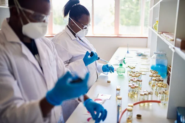 Afrikai Női Technikus Védőmaszkban Szemüvegben Laboratóriumi Mintákat Ellenőriz Miközben Egy Jogdíjmentes Stock Fotók