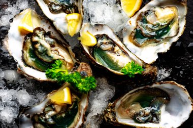 Çiğ, limon ve maydanozla ezilmiş buzda istiridye açtı.
