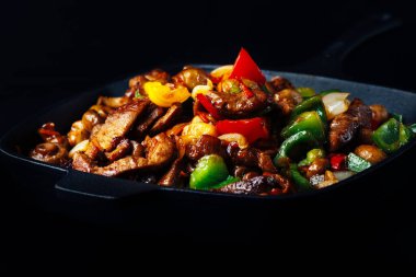 Dökme demir tavada kızarmış et ve sebze karışımı.
