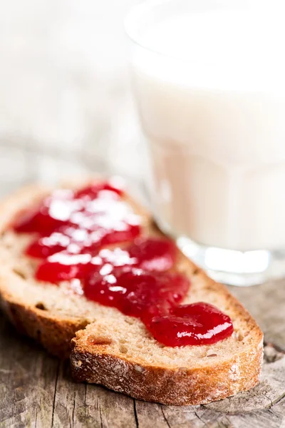 Pan con esparcimiento de fresa y vaso de leche — Foto de Stock