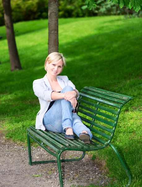 Woman sitting on bench in park vertical — Stock Photo, Image
