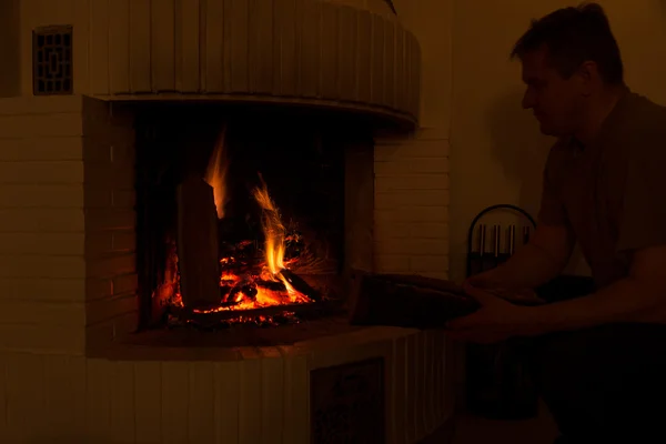 Man adding firewood to fireplace — Stock Photo, Image