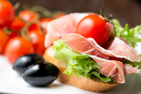 Prosciutto mit Oliven und Tomaten auf Brot — Stockfoto