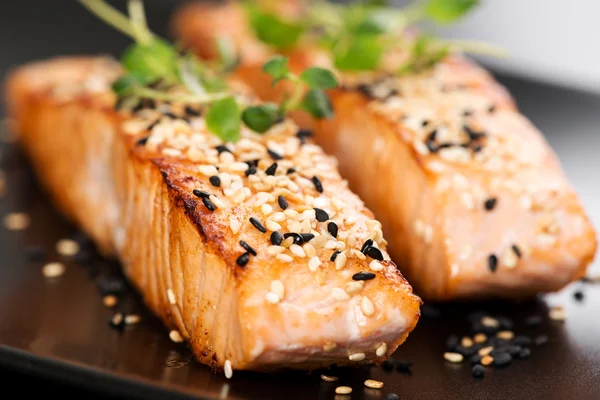 Grilled salmon on black plate — Stock Photo, Image