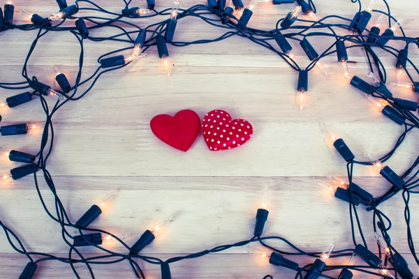 Guirnalda de luces con forma de corazones rojos sobre fondo de madera —  Fotos de Stock