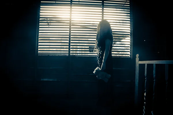 Таинственная девушка в черном платье, стоящая в заброшенном доме — стоковое фото