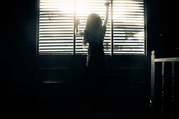 Chica misteriosa en vestido negro de pie en abandonar la casa de la mano en la ventana — Foto de Stock