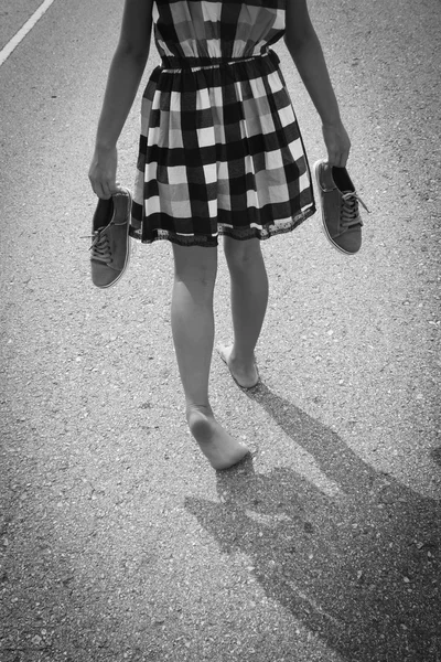 Menina andando descalça na estrada de asfalto — Fotografia de Stock