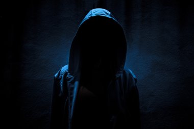 Woman wearing hoodie hiding in the dark,Scary background for book cover clipart