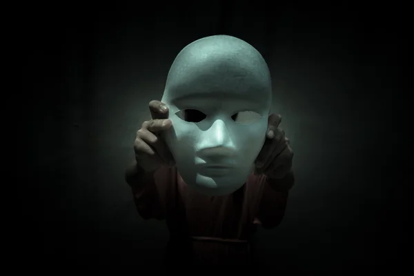 Таинственный человек, показывающий белую маску в темноте, страшный фон для обложки книги — стоковое фото