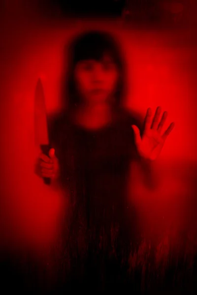 Woman with knife screaming behind stained or dirty window glass — Stock Photo, Image