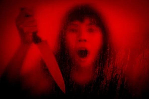 Woman with knife screaming behind stained or dirty window glass — Stockfoto